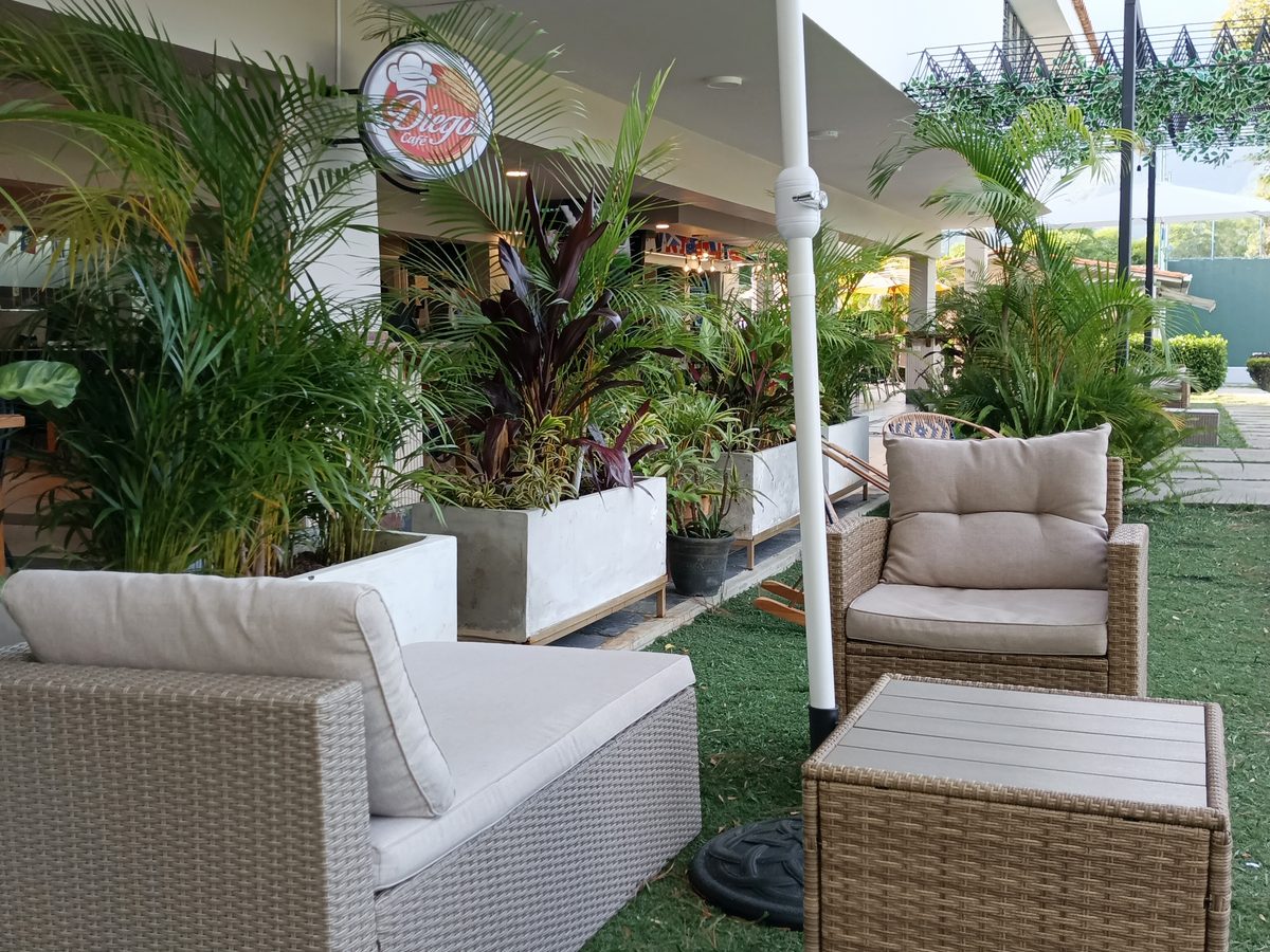 Terraza del club con sombrilla y sofás de mimbre