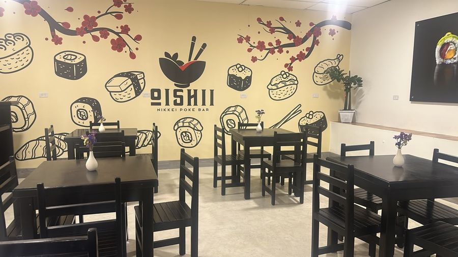 Local japonés del club, con mesas oscuras y un mural de sushi