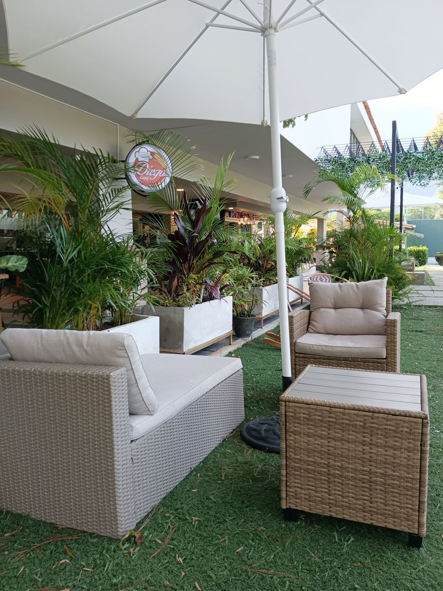 Terraza con sombrilla y sofás de mimbre sobre el césped