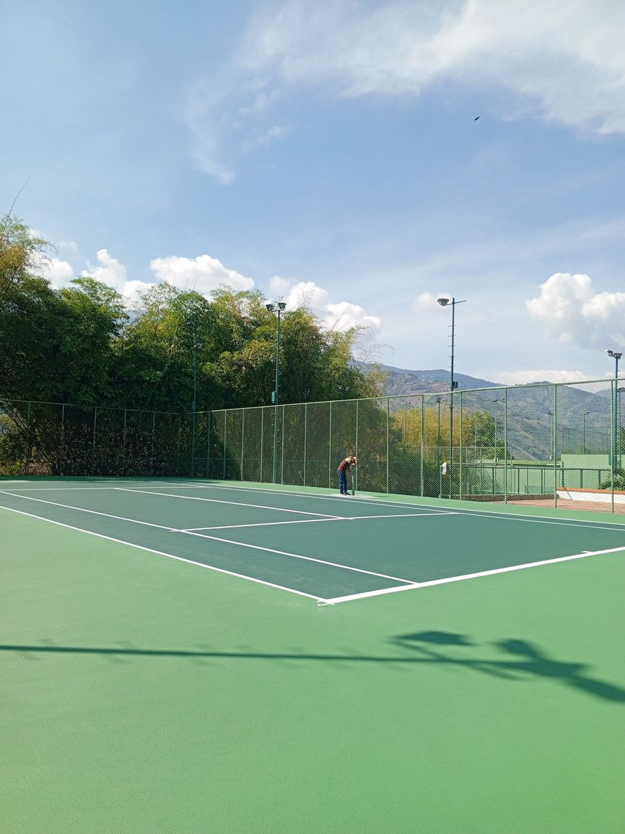 Cancha de tenis vista desde el fondo, con las torres de luz
